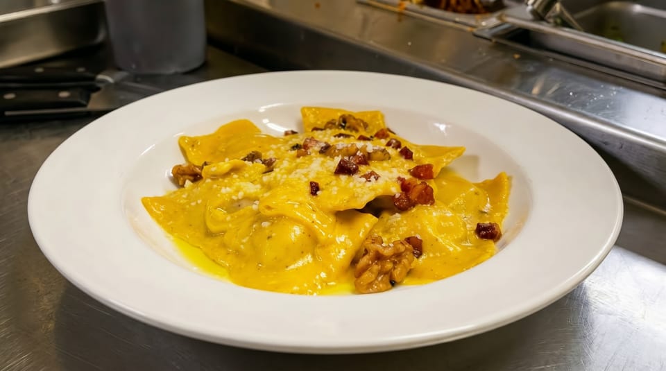 Plate of golden ravioli in a creamy sauce, topped with walnuts, bacon bits, and grated cheese.