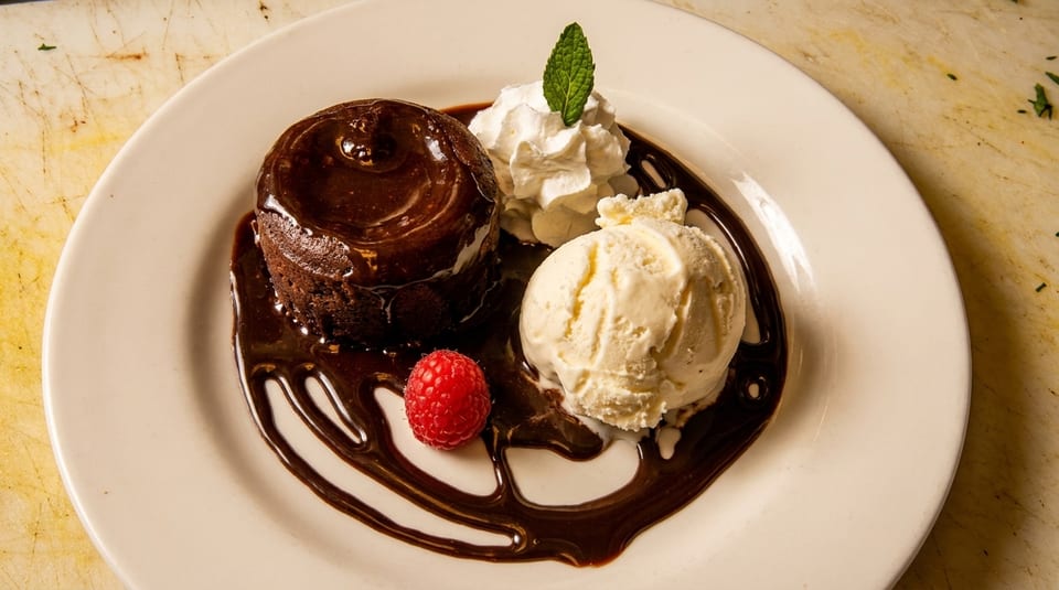 Chocolate lava cake with chocolate syrup, vanilla ice cream, whipped cream, raspberry, and mint.